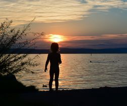 Kind im Sonnenuntergang am See